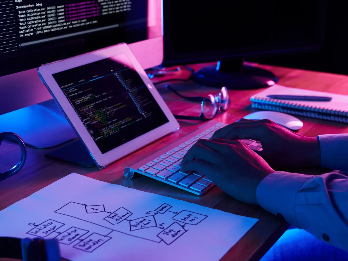 Desarrollador programando junto a un diagrama de flujo con las especificaciones del sistema